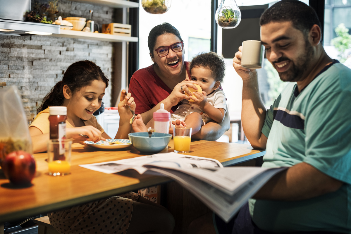 Decorative photo of a Latino family of four eating at kitchen counter