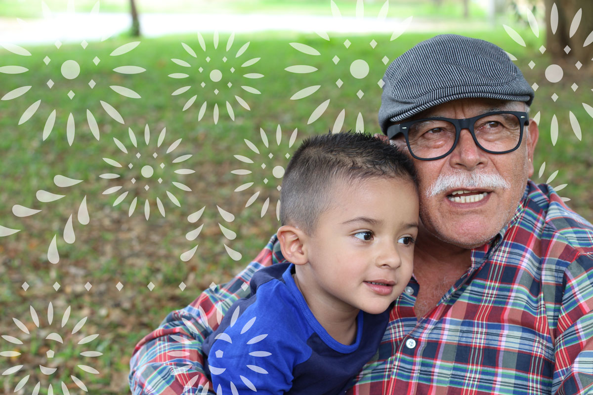 Decorative photo of a man embracing a young child at a park.