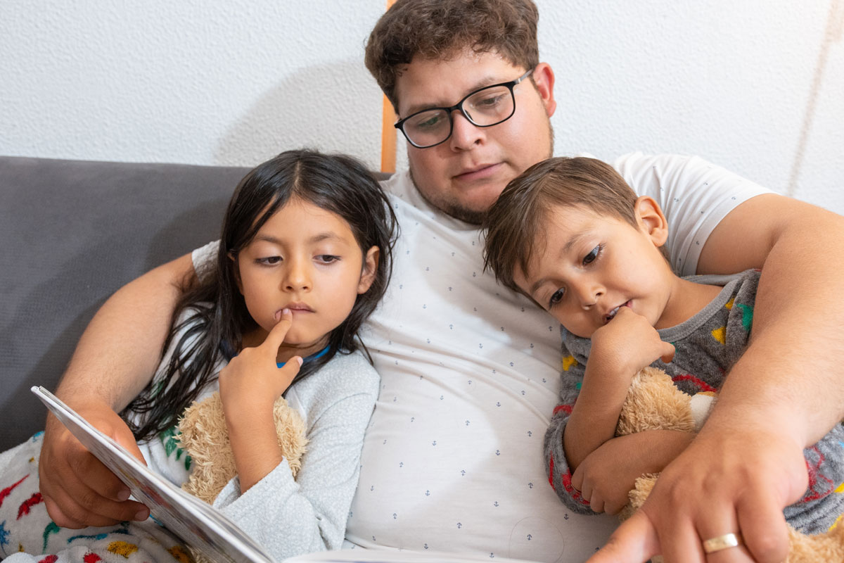 Decorative photo of a man reading to two young children in pajamas.